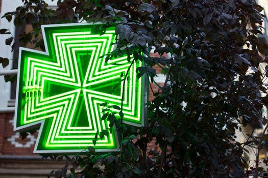 A green-lit pharmacy sign in Madrid