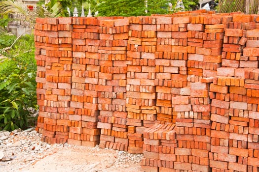 Lots of red brick. The stacked into a wall to be used in construction.