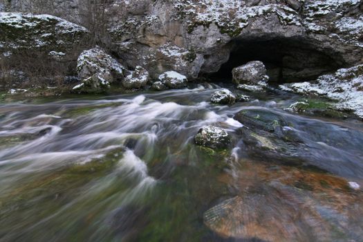 Rapid river emerging from within a cave. Motion water.