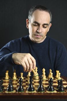 Man moving a chess piece on wooden chessboard
