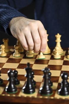 Hand moving a pawn chess piece on wooden chessboard as first move