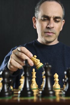 Man moving a chess piece on wooden chessboard