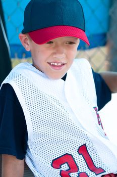 Little league baseball player watching from the dugout.