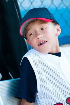 Little league baseball player smiling in dugout.