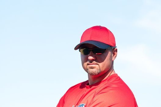 Baseball coach wearing sunglasses and looking at camera.