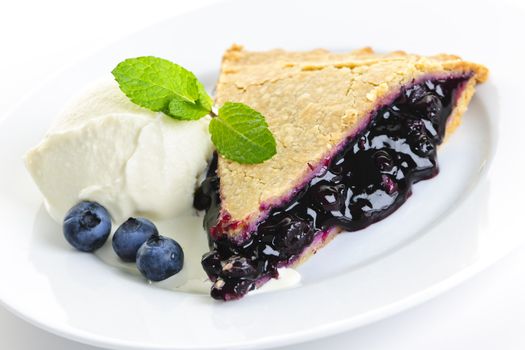 Slice of blueberry pie with vanilla ice cream and berries