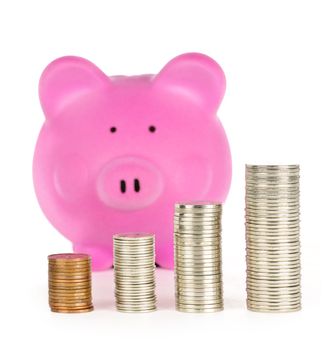 Stacks of coins in front of pink piggy bank showing growth