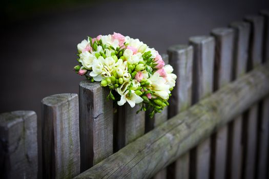 Wedding bouquet with roses and freesia on rustic country fence