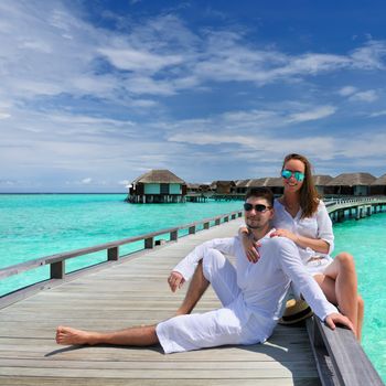 Couple on a tropical beach jetty at Maldives