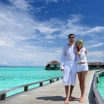 Couple on a tropical beach jetty at Maldives