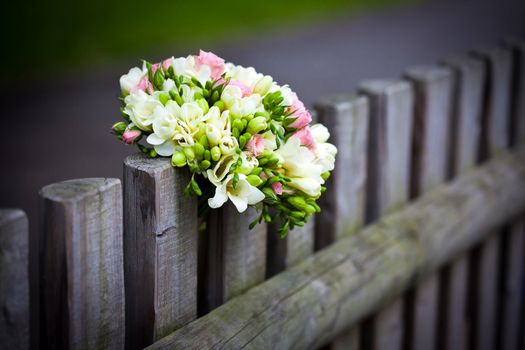 Wedding bouquet with roses and freesia on rustic country fence