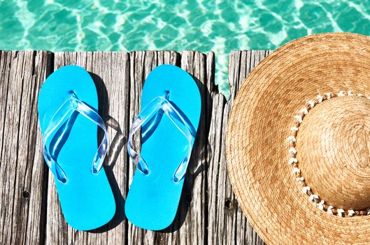 Slippers and hat at jetty by the sea