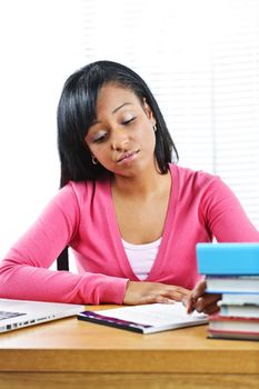 Young black female student studying at desk looking sad