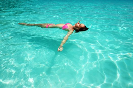 Woman in bikini lying on water at tropical beach