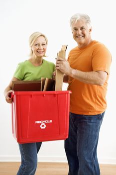 Man and woman smiling while holding recycling bin.