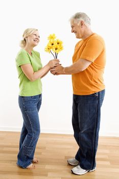 Middle-aged man giving woman bouquet of yellow flowers.