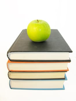 green apple with books isolated in white