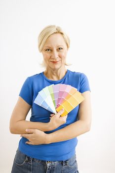 Portrait of smiling adult blonde woman holding paint swatches.