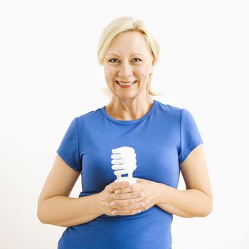 Portrait of smiling adult blonde woman holding energy-saving lightbulb.