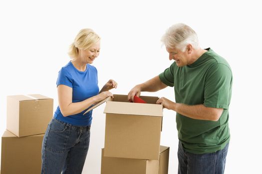 Middle-aged couple packing or unpacking moving boxes.