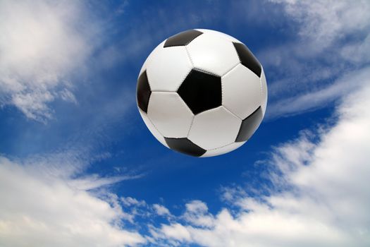 football soccer ball under blue sky with clouds