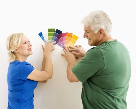 Middle-aged couple comparing and discussing paint swatches.