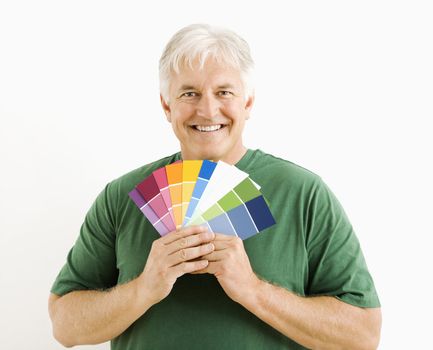 Middle-aged man holding up paint swatches.