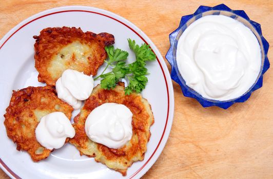 potato pancakes on plate with sour cream