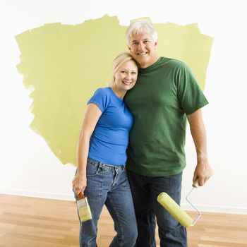 Middle-aged couple in front of wall they are painting green.