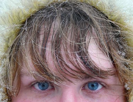 winter, woman's blue eyes and hair under snow