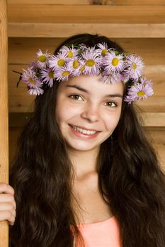 Portrait of the beautiful young girl in a wreath from lilac camomiles
