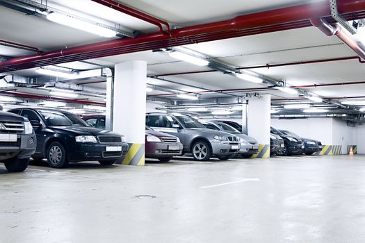 The shined underground garage with the moving cars and parked cars
