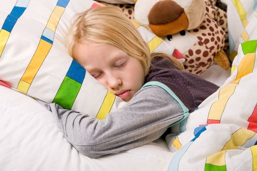 Sleeping young cute child in a colorful bed