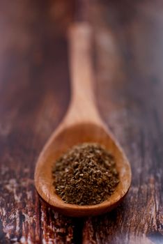marjoram spice in wooden spoon over wood background - selective focus