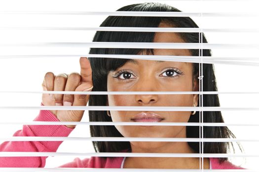 Young black woman looking through horizontal venetian blinds