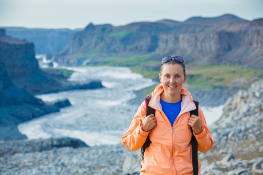 Cute woman hiking in the canyon Dettifoss waterfall in Vatnajokull National Park, Northeast Iceland.