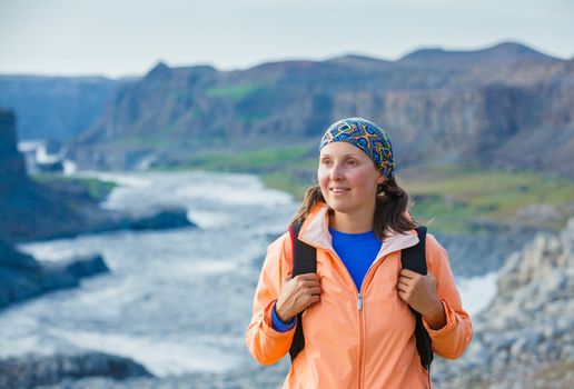 Cute woman hiking in the canyon Dettifoss waterfall in Vatnajokull National Park, Northeast Iceland.