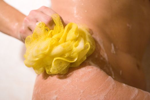 Woman with a yellow bathroom sponge taking a shower.