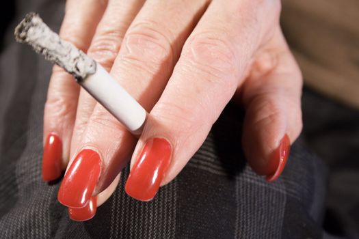 Mature woman with painted fingernails smoking a cigarette.