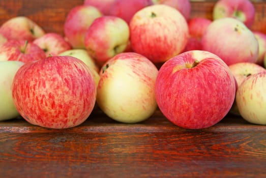 Red apples laying on wooden bench