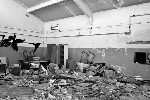 Vandalized equipment and debris in derelict factory. Black and white.