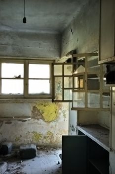 Dusty cabinets and textured wall in empty room. Abandoned house interior.