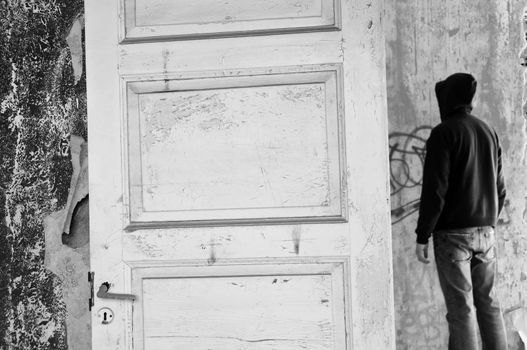Hooded figure in abandoned house. Black and white.