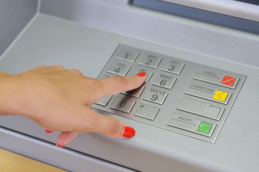 Hand entering pin on ATM