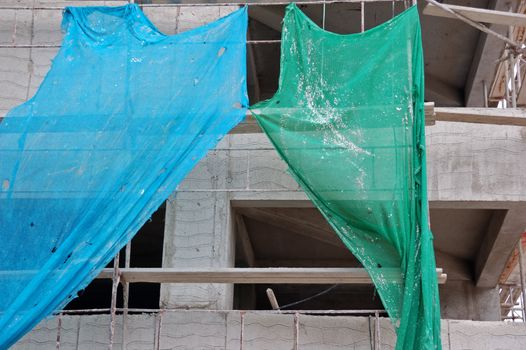 Ragged debris netting and scaffold on concrete unfinished building.