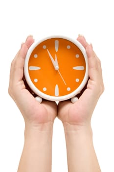Hands holding an orange alarm clock. Showing five minutes to midnight. Isolated on a white background.