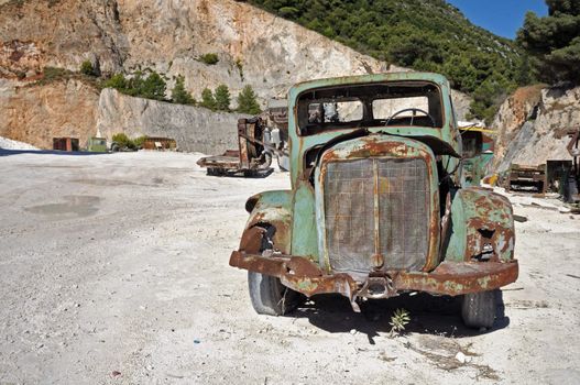 Rusty vintage car and industrial machinery at a quarry.