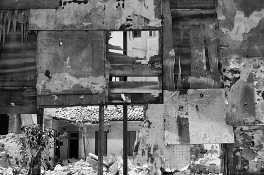 Ruins and rubble behind tattered billboard. Black and white.
