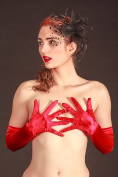 Portrait of a nude models with hidden and elaborate hairstyle with hair bow and red gloves
