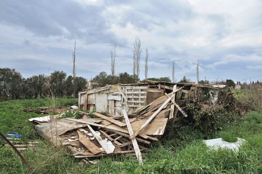Collapsed wooden hut ruins and overcast sky.
